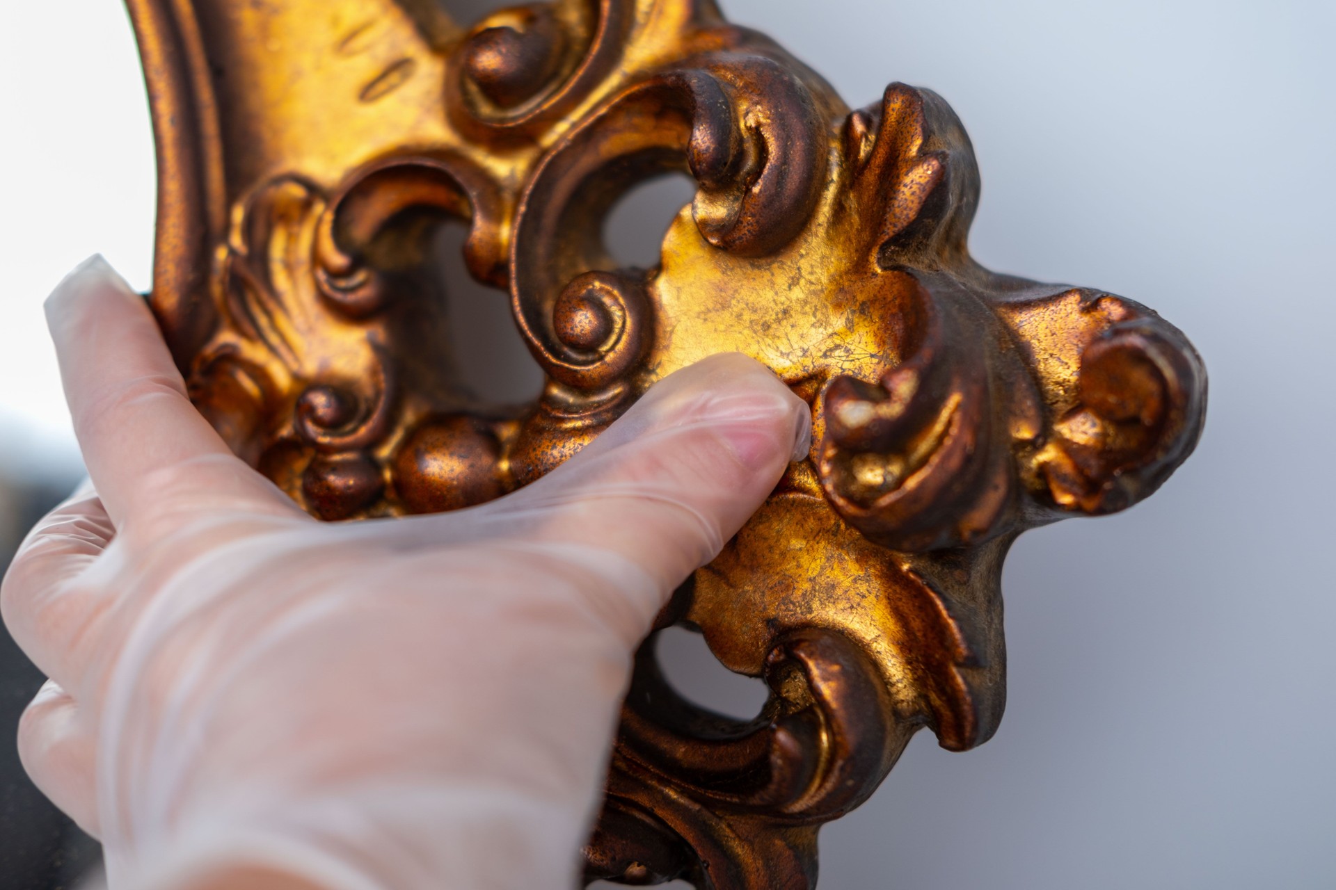 Art conservator restoring golden mirror frame, antique detail closeup, delicate brushwork, cleaning, preparing for art auction, Careful restoration, heritage care