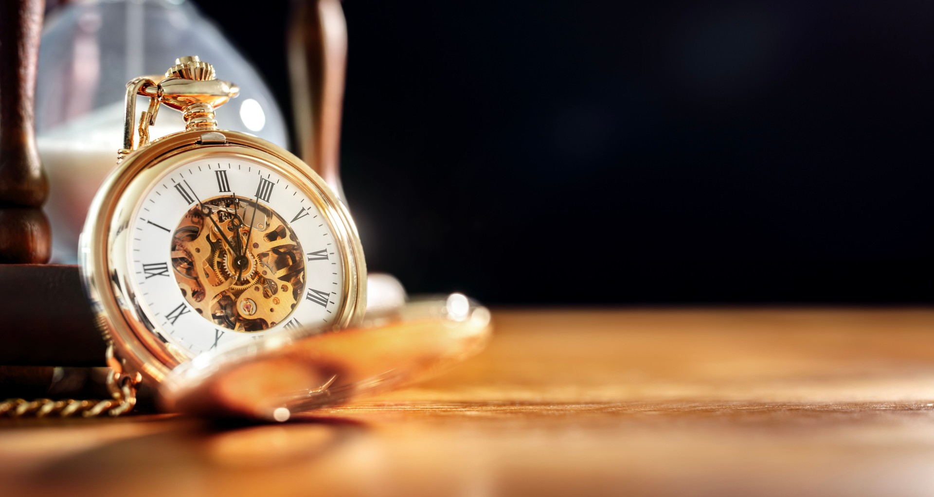 Gold pocket watch and hourglass background